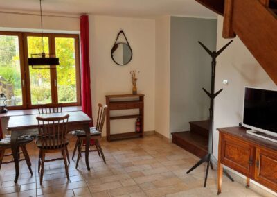 Blick vom Sofa aus in dem Wohnbereich mit Tisch, Stühlen, Fernseher, Garderobe, Spiegel