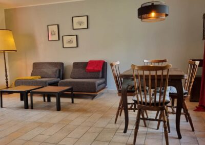 Wohnbereich mit Sofa, Tisch und vier Stühlen aus Holz
